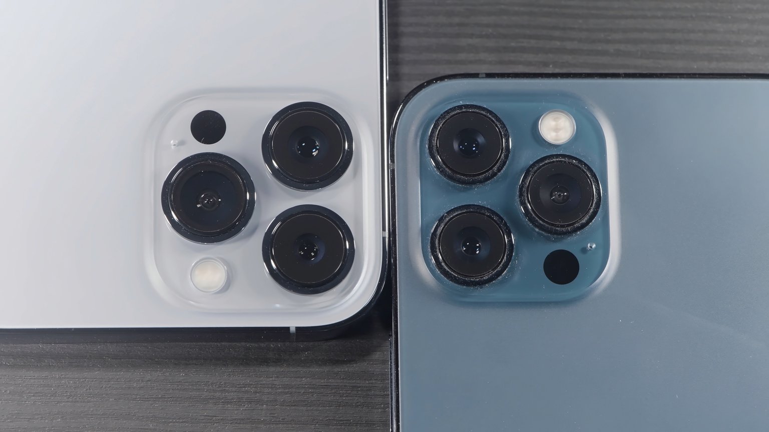 Saint Petersburg - Russia, 10.11.2021: Close up of Three Cameras of New IPhone 13 Pro Max. Action. Stylish Design and Professional Cameras of New Blue and Silver Smartphones Lying on Wooden Surface.