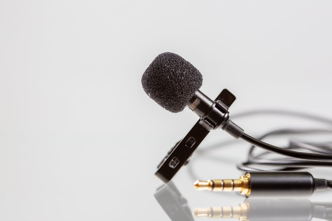 Small lavalier microphone or lapel mic with clip on white background. Professional sound recording equipment for cell phone.